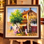 Tranh Nắng Qua Phố Cũ với mái ngói đỏ, cây xanh và nhịp sống phố nhỏ trong khung gỗ